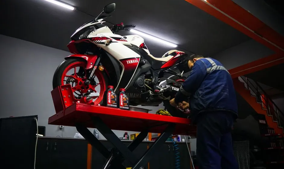 Moto sur béquille d'atelier, outils et chiffon posés au sol, entretien maison